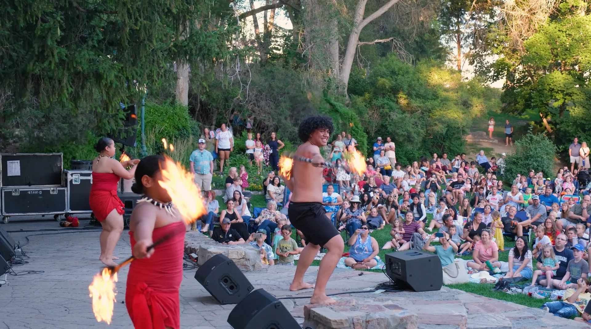 A man and a woman are dancing with fire in front of a crowd.