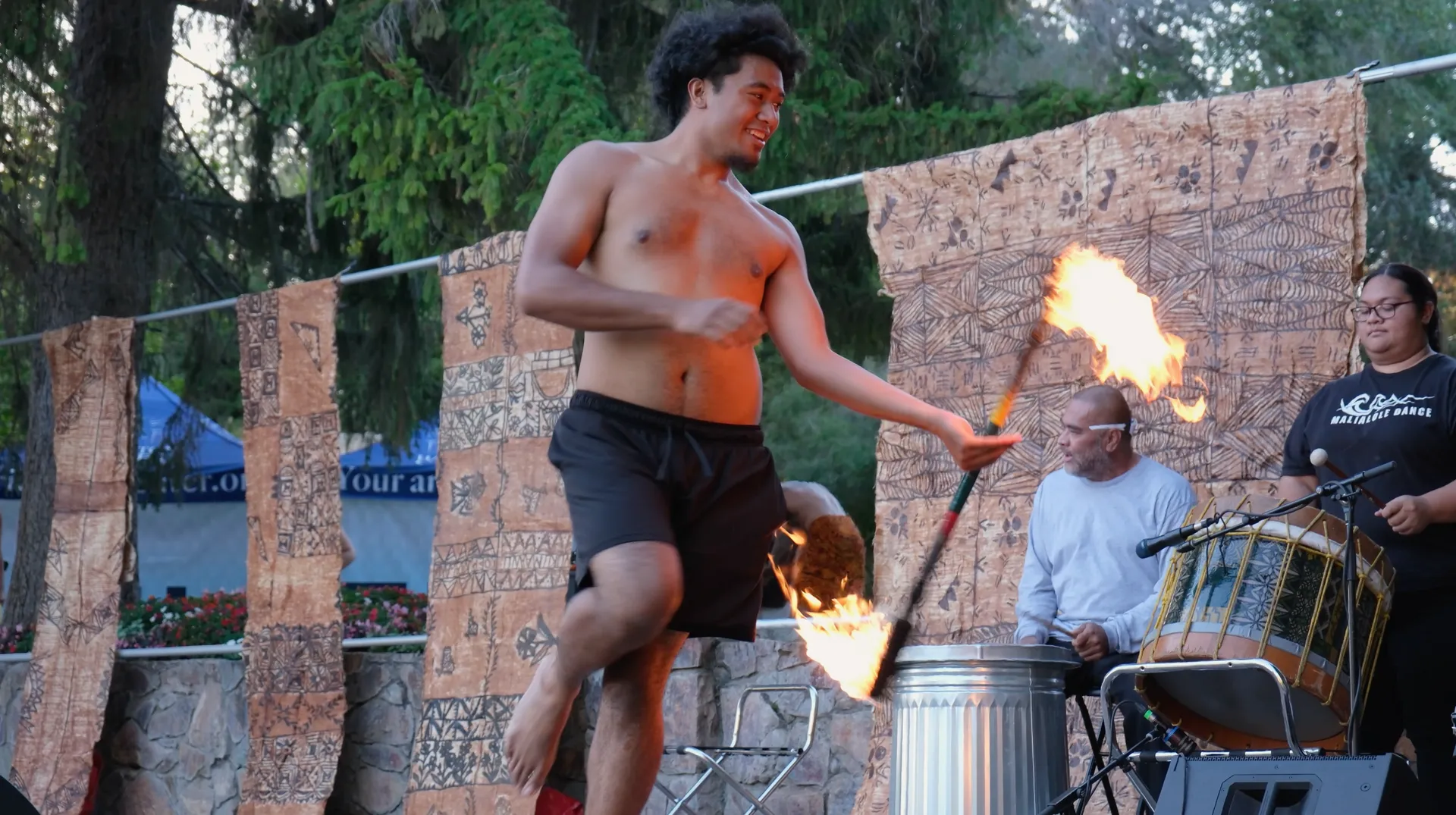 A man without a shirt is holding a fire torch in his hand.