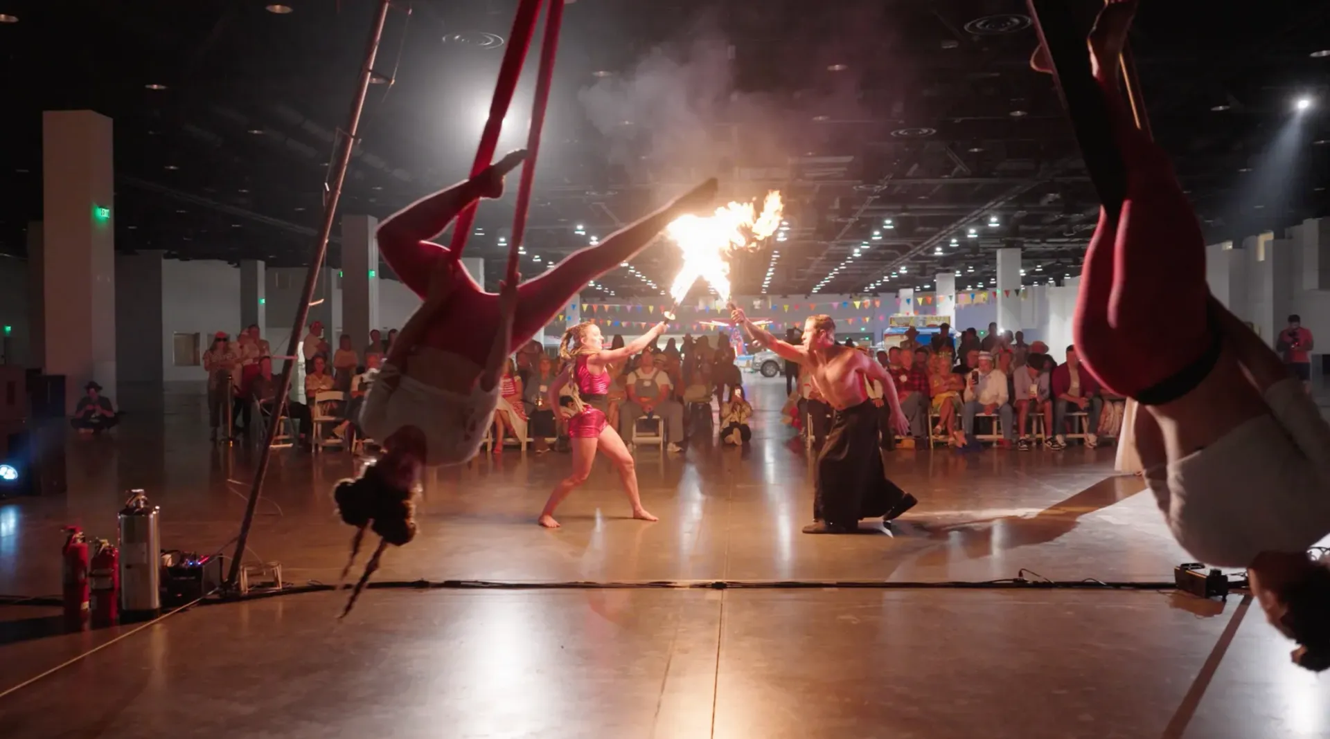 A group of people are performing aerial acrobatics in a large room.