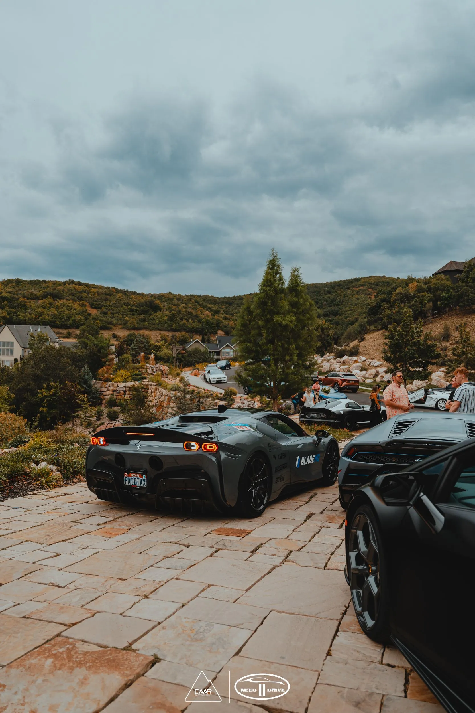 A couple of sports cars parked next to each other on a brick driveway.
