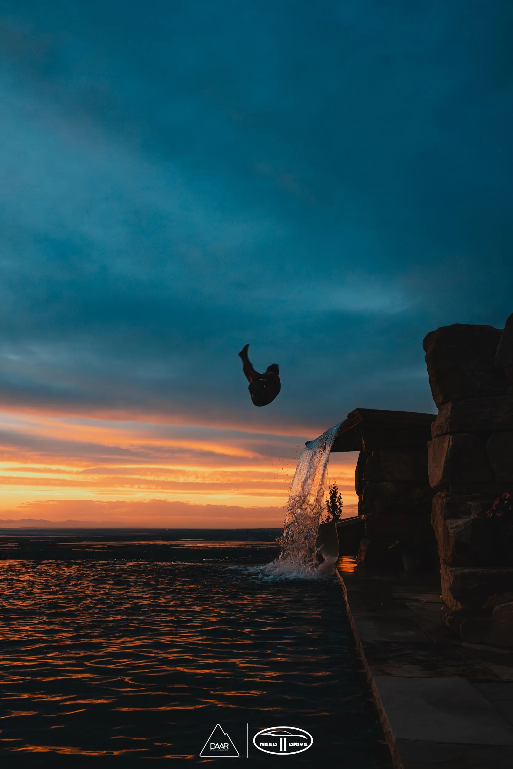 A person is jumping into the water at sunset.