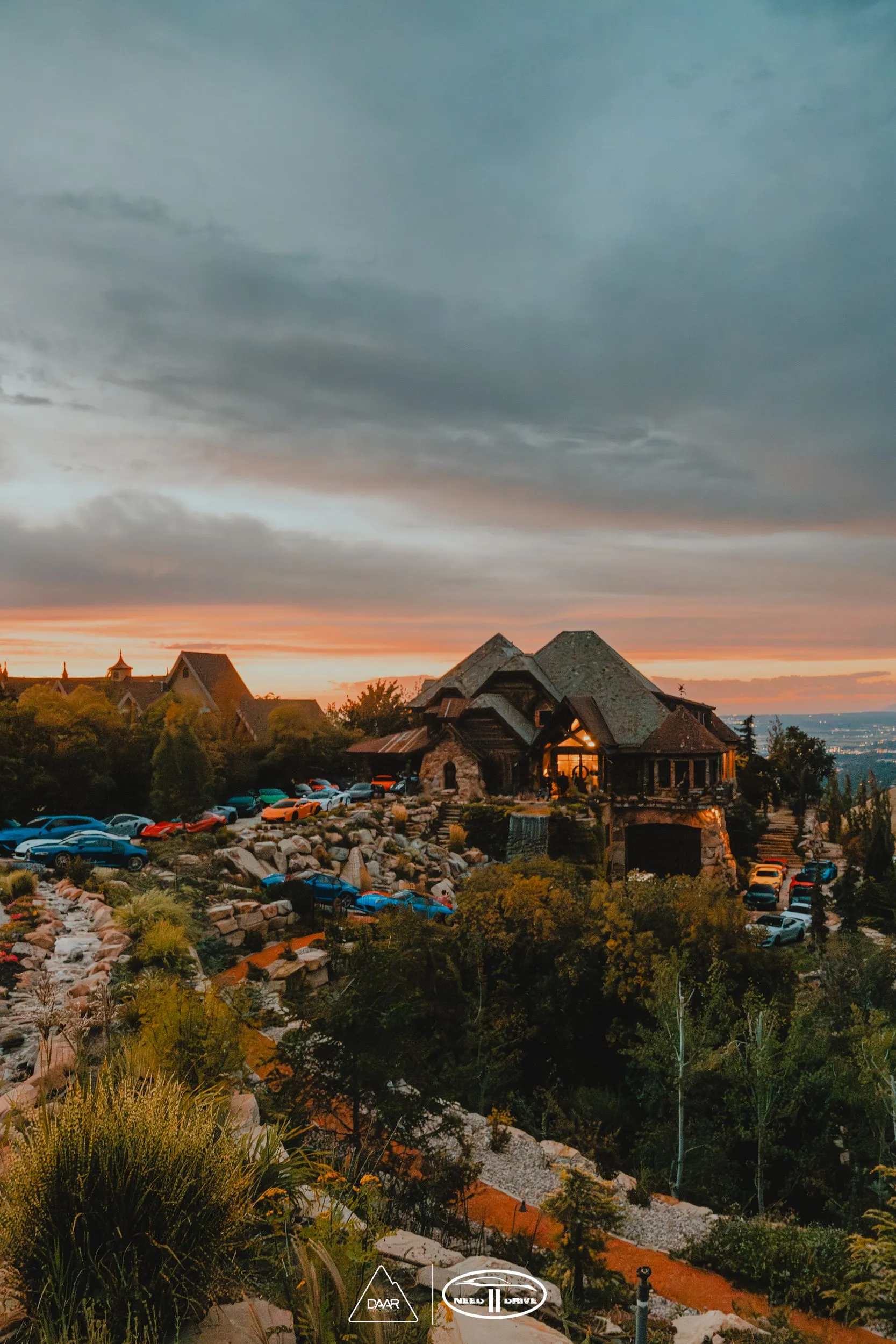 An aerial view of a house on top of a hill at sunset.