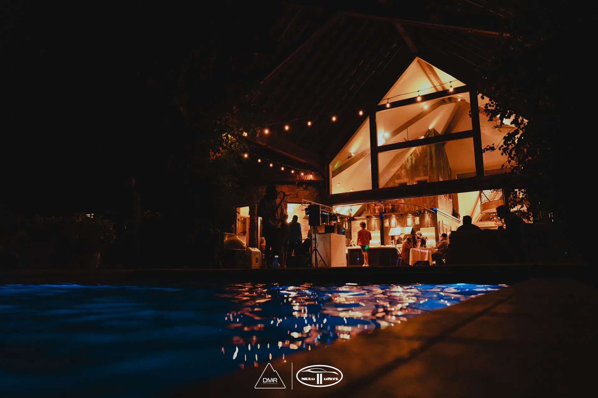 A large building with a swimming pool in front of it at night.