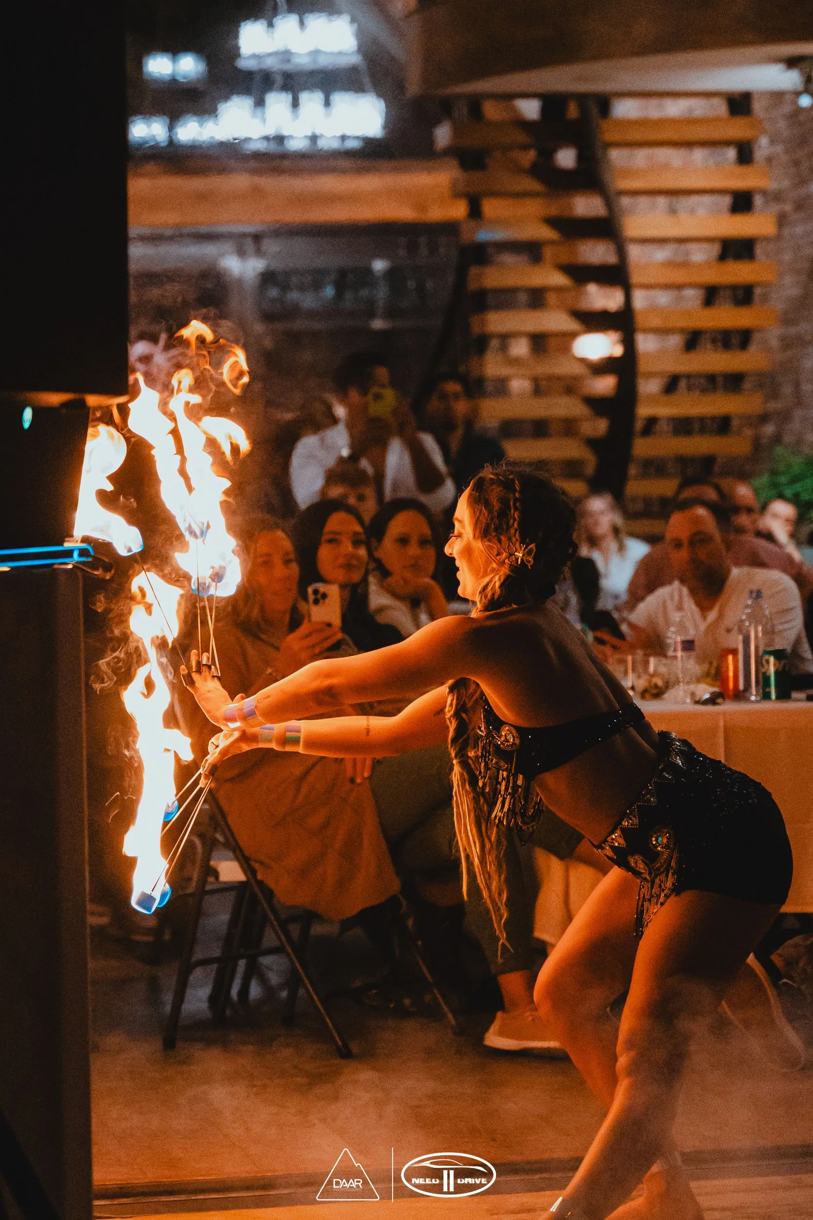 A woman is dancing with fire in front of a crowd of people.