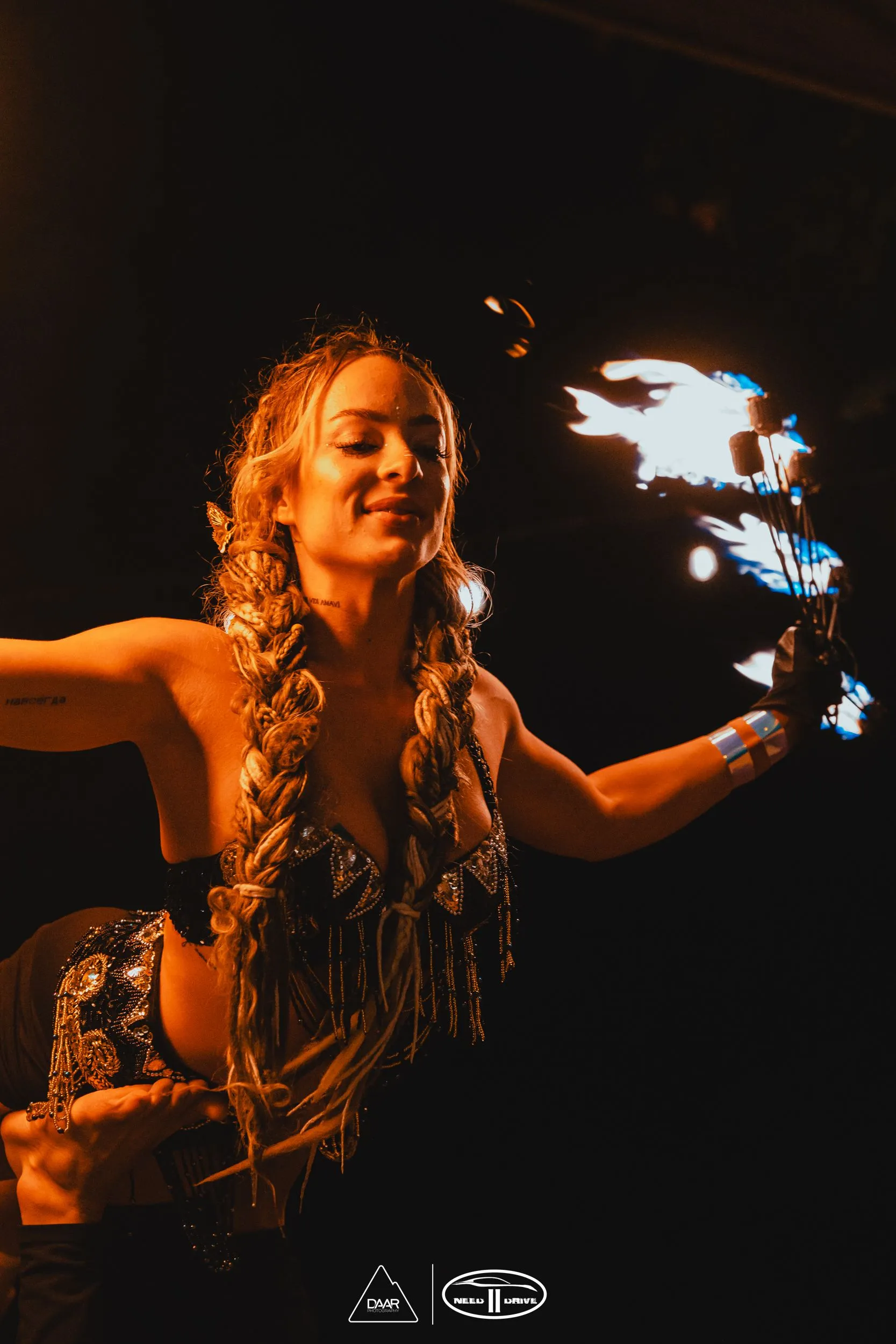 A woman is holding a fireball in her hand in the dark.