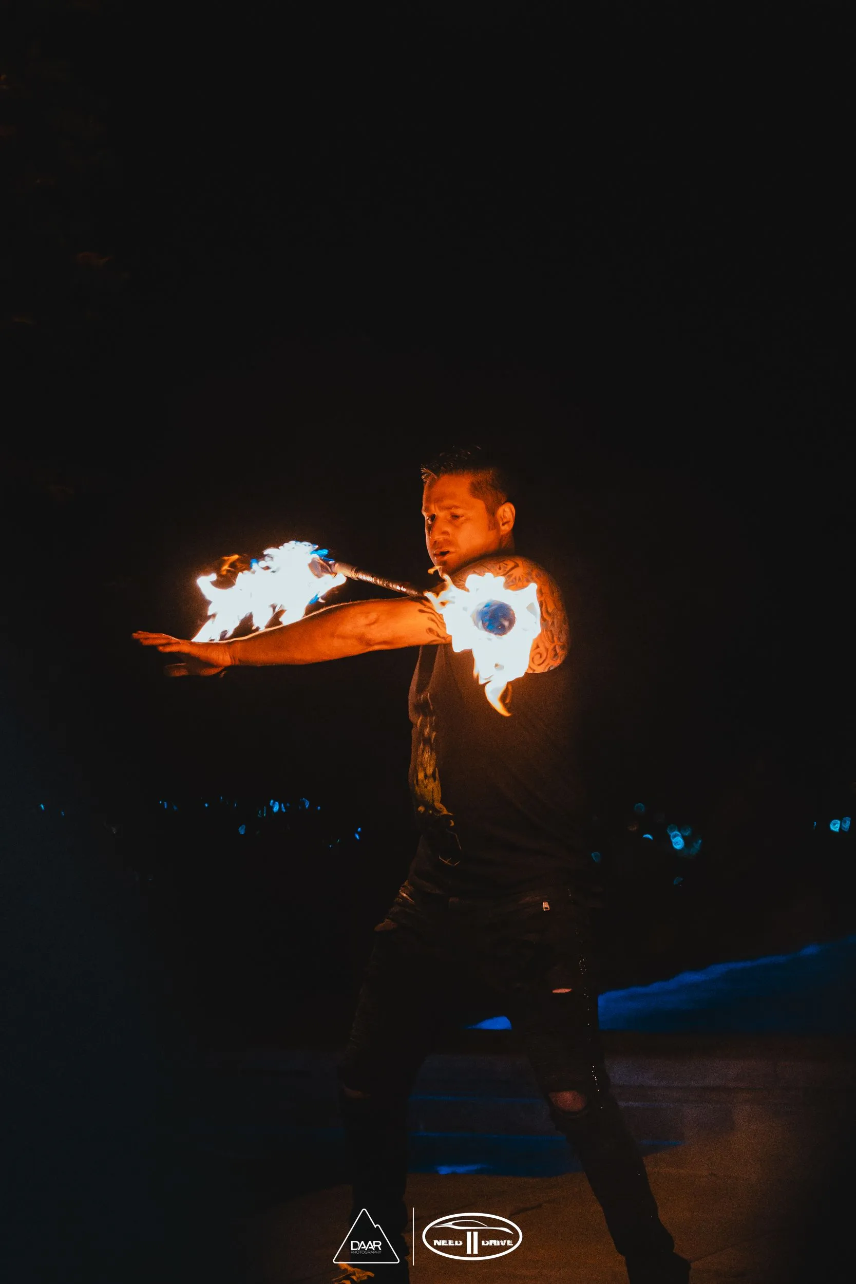A man is holding a stick of fire in his hand in the dark.