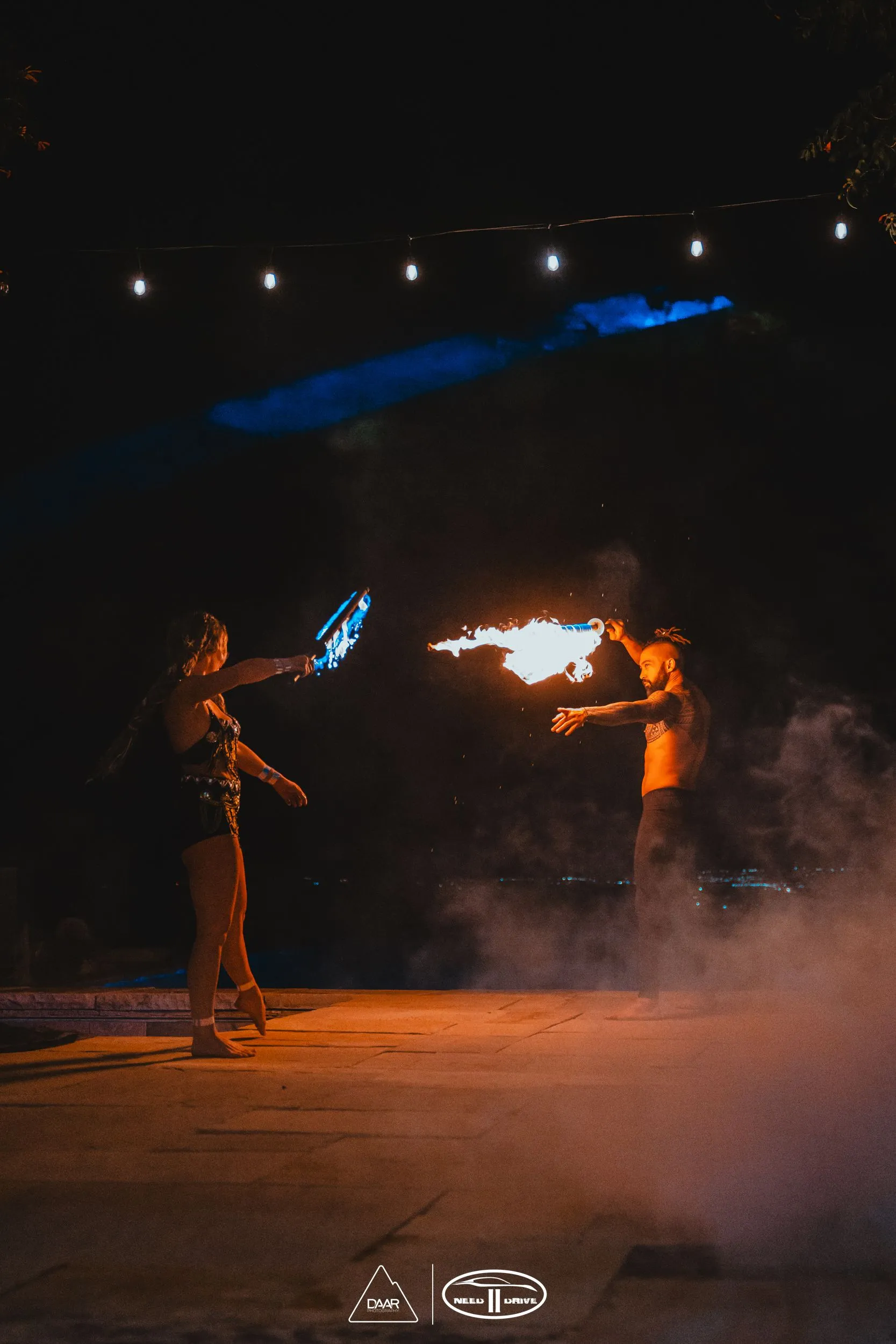 A man and a woman are playing with fire on a stage at night.