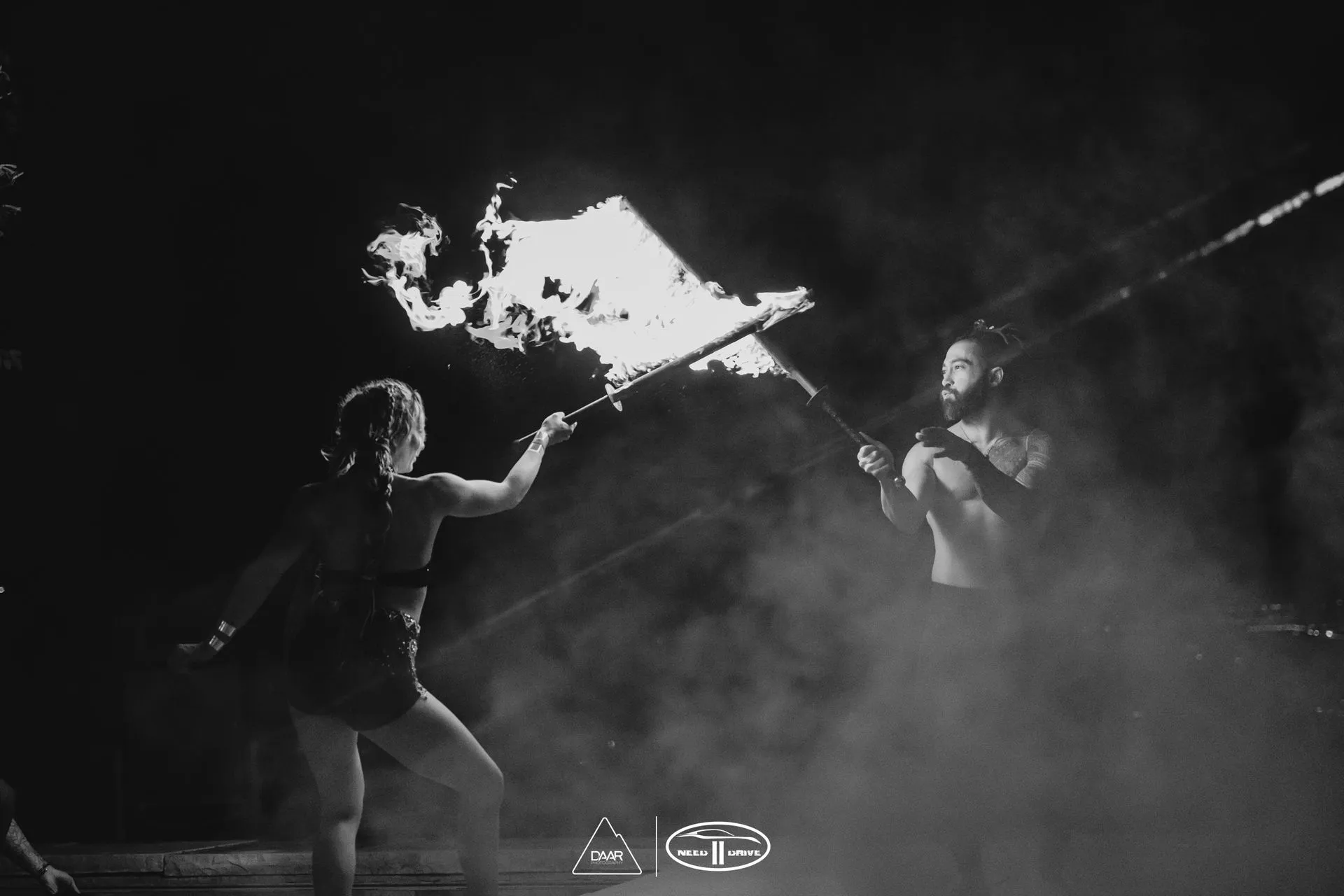 A man and a woman are holding a fire torch in a black and white photo.