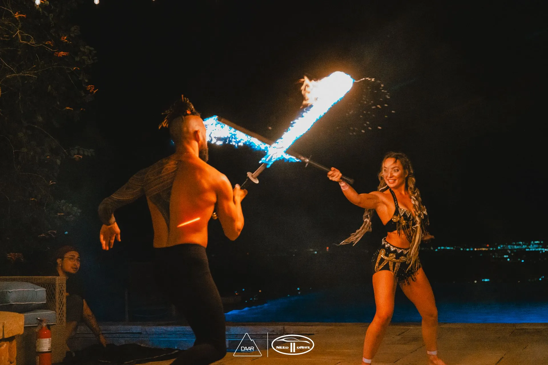 A man and a woman are holding fire swords in their hands.