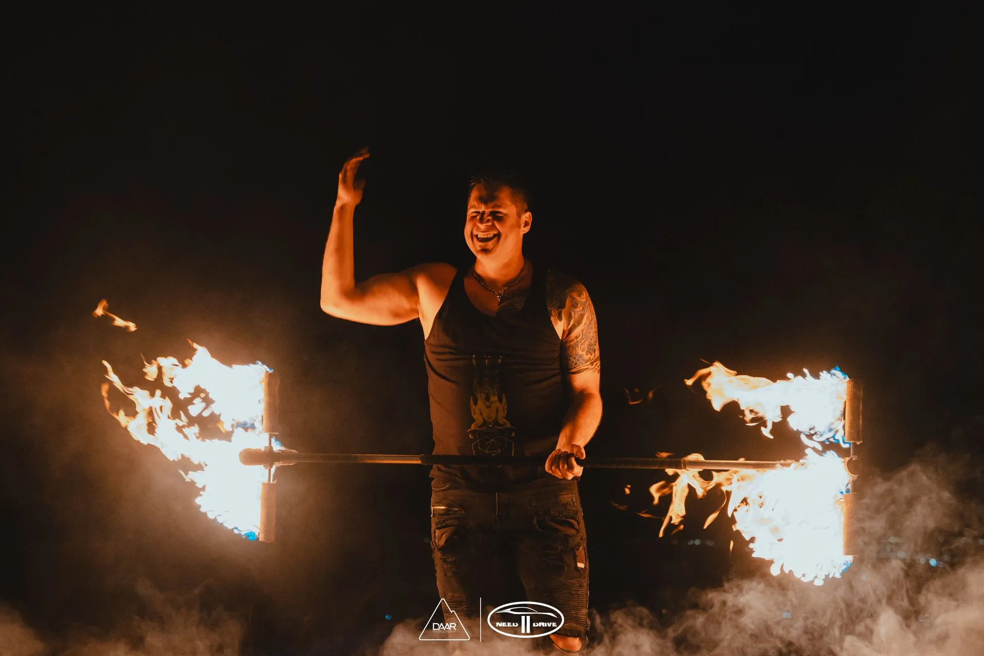 A man is holding a stick with flames on it in the dark.