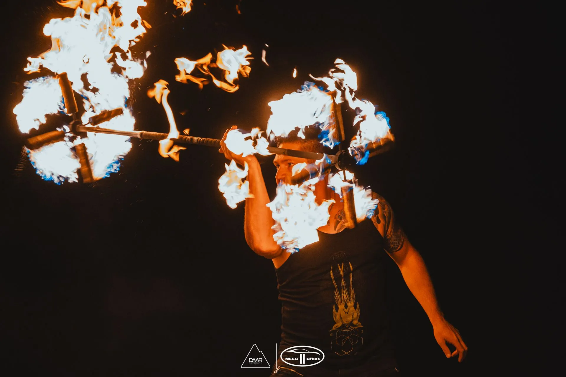 A man is holding a stick with flames coming out of it.