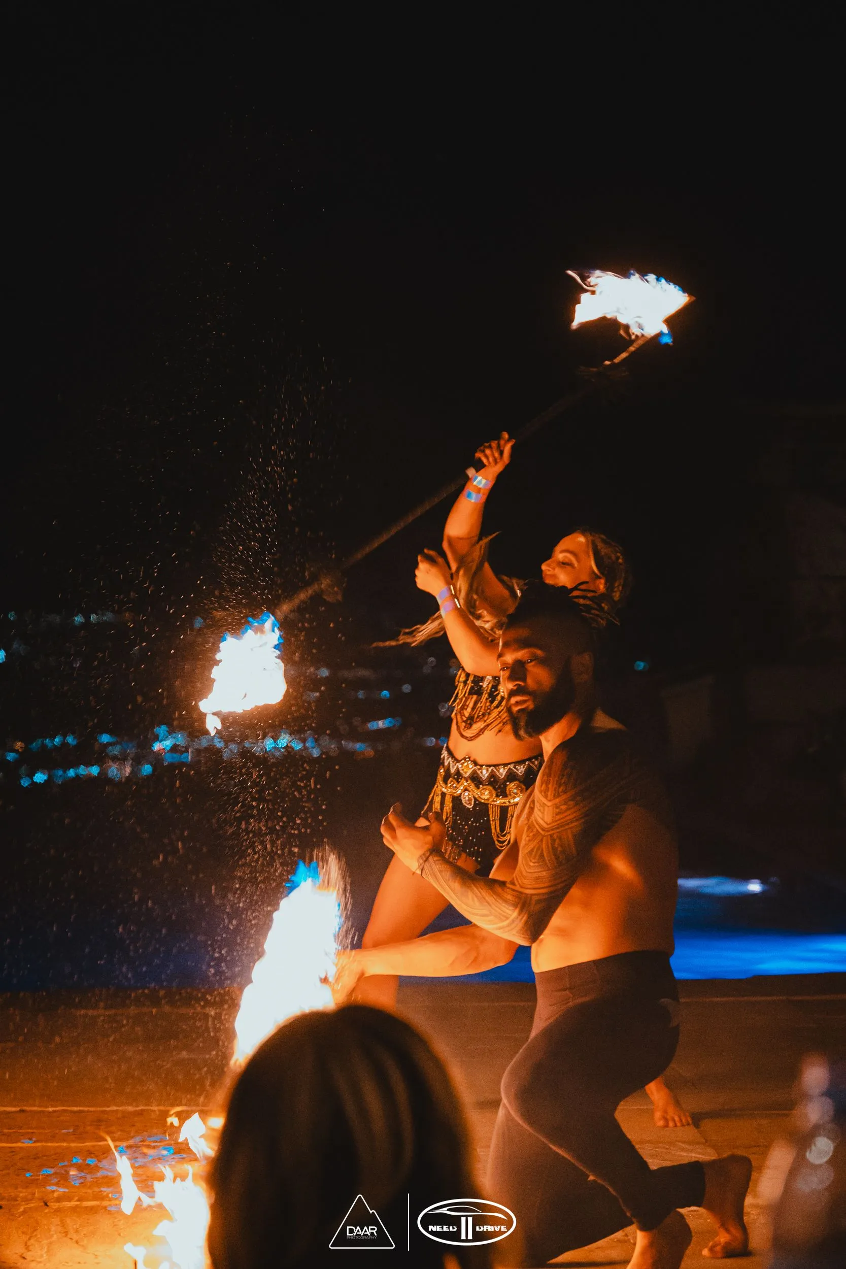 A man and a woman are dancing in front of a fire.