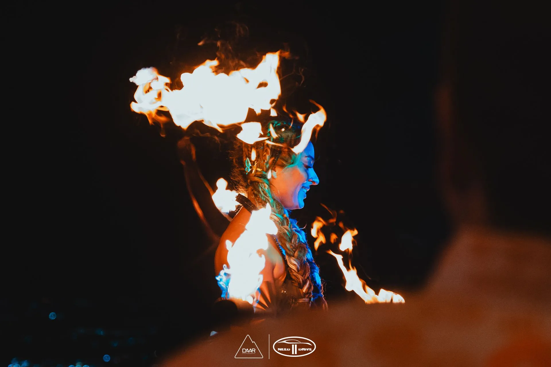 A woman is surrounded by flames in the dark.