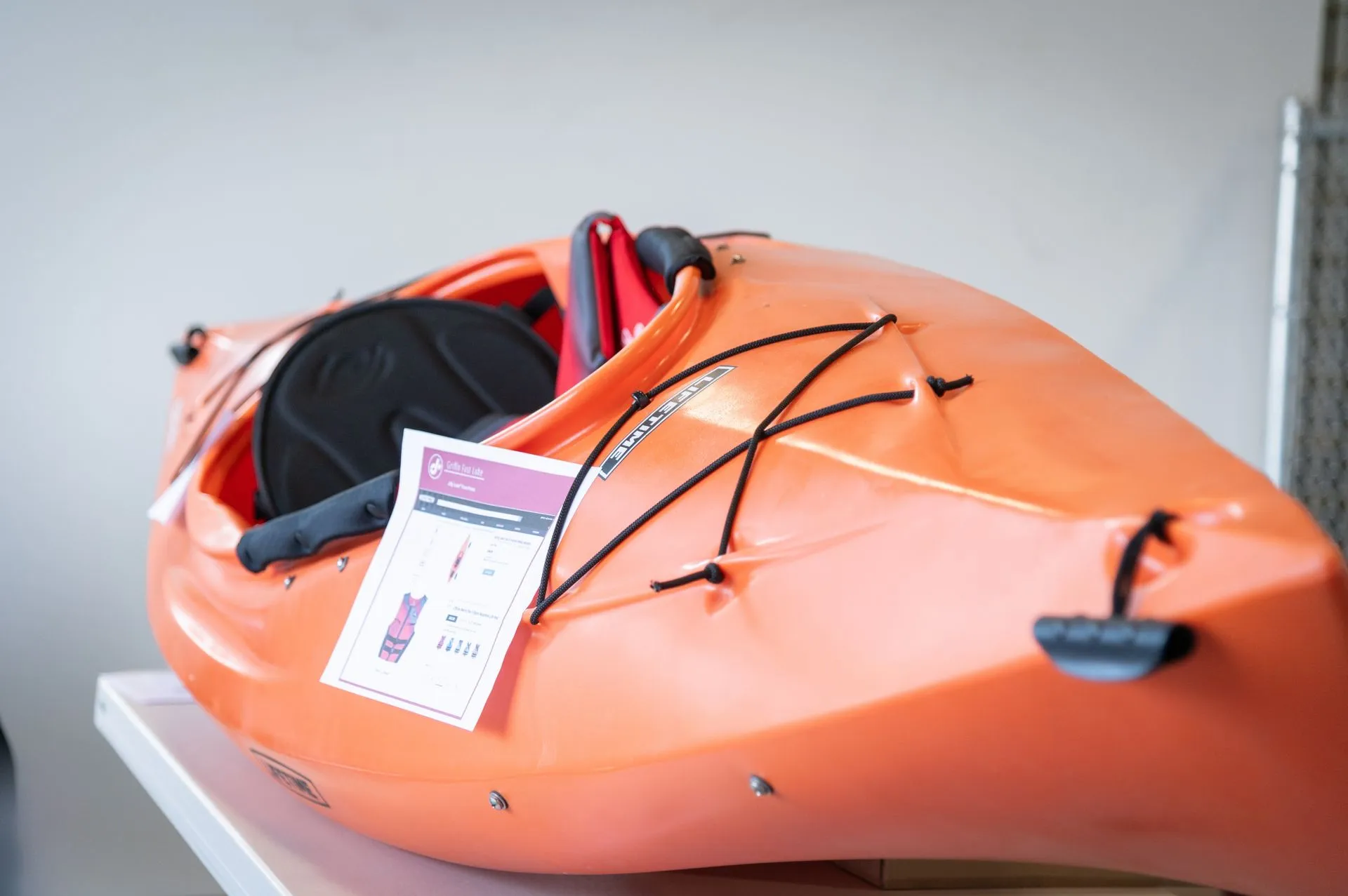 An orange kayak is sitting on top of a white table.