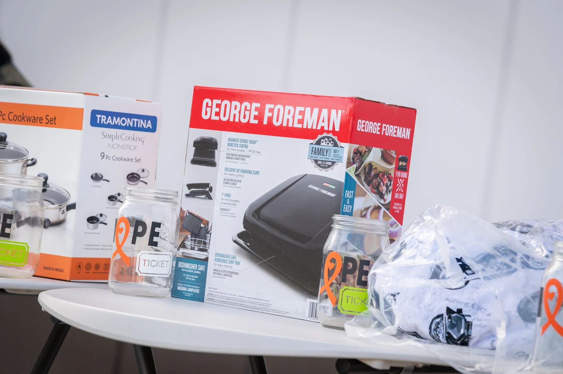 A table with a george foreman box , glasses , and a george foreman grill.