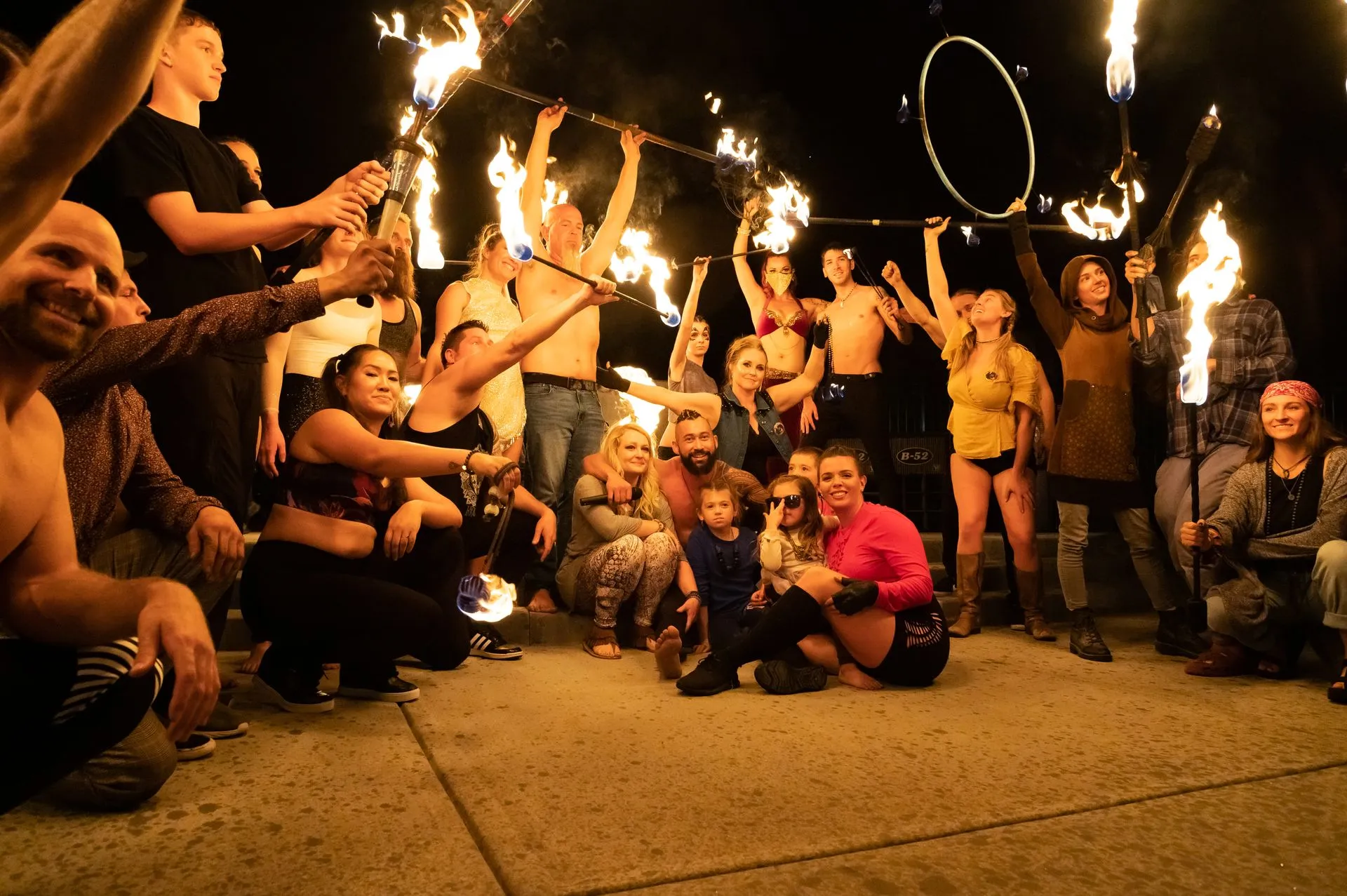 A group of people are posing for a picture while holding fire sticks.