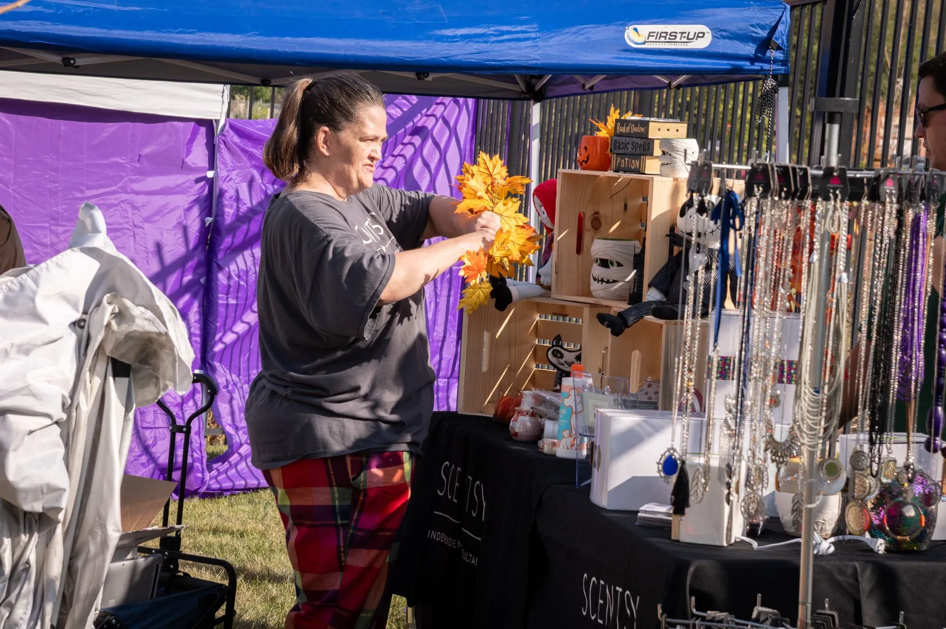A woman is standing in front of a table at a market.