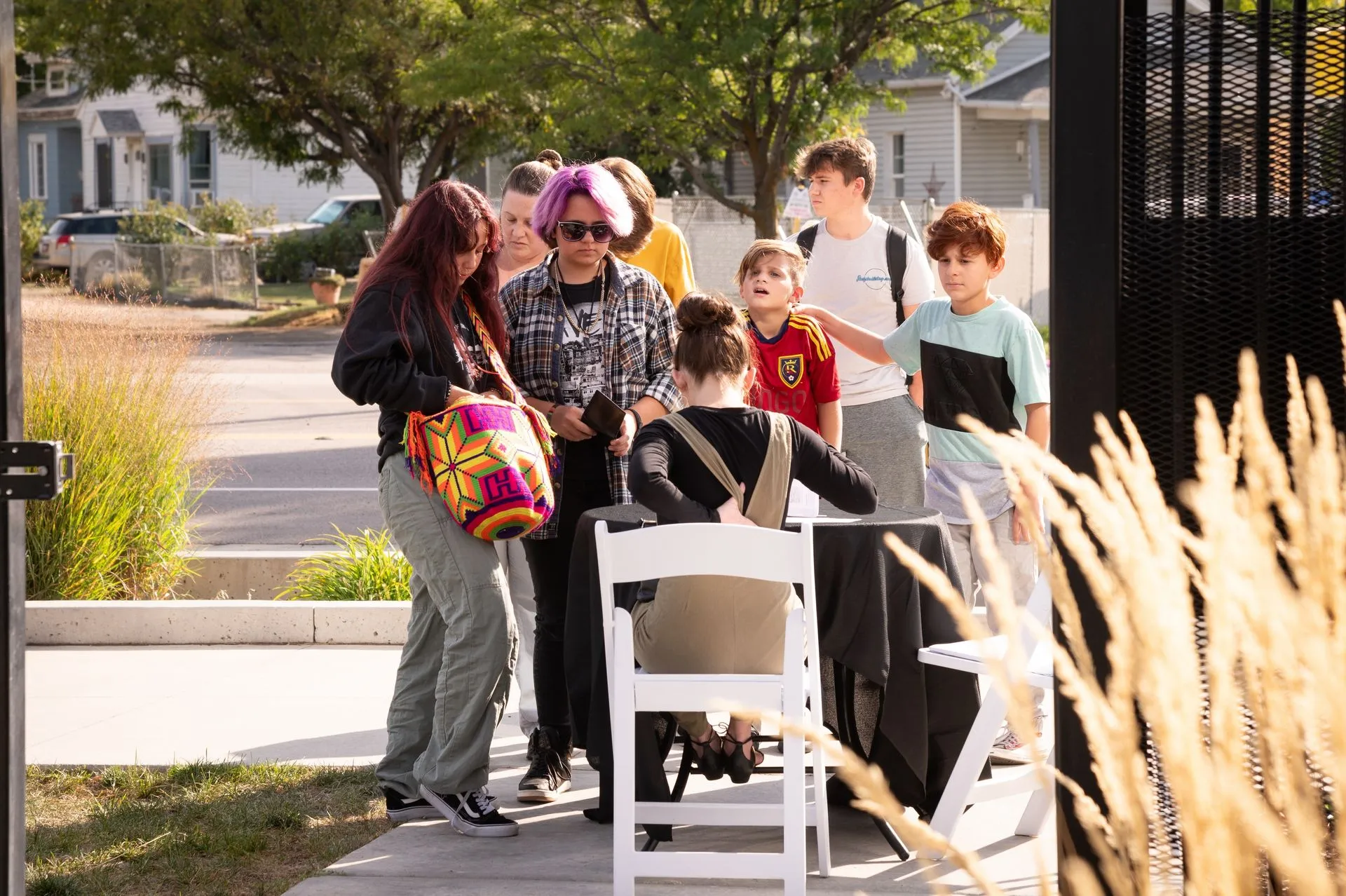 A group of people are standing around a table in a park.