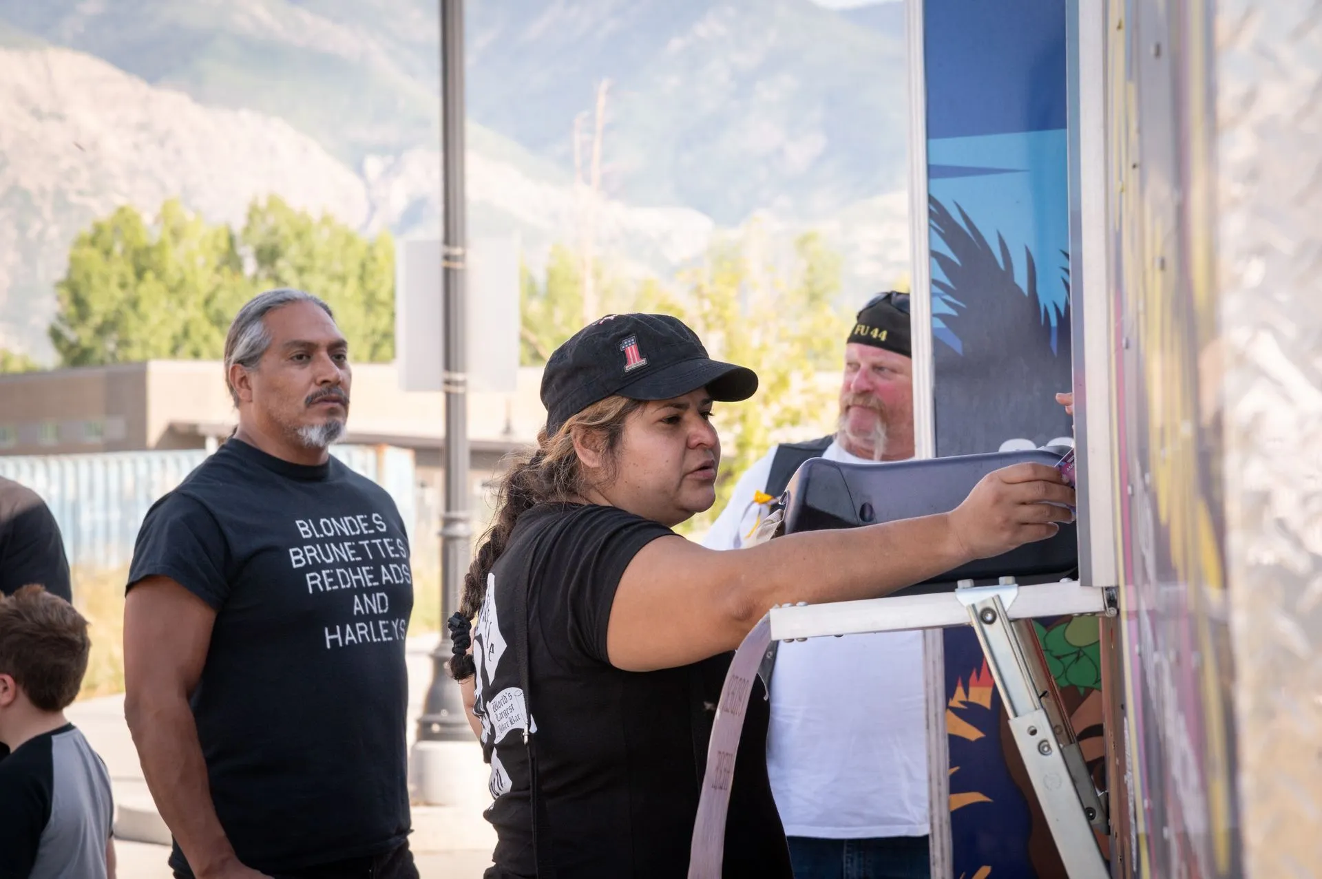 A woman is standing on a ladder painting a picture on a wall.