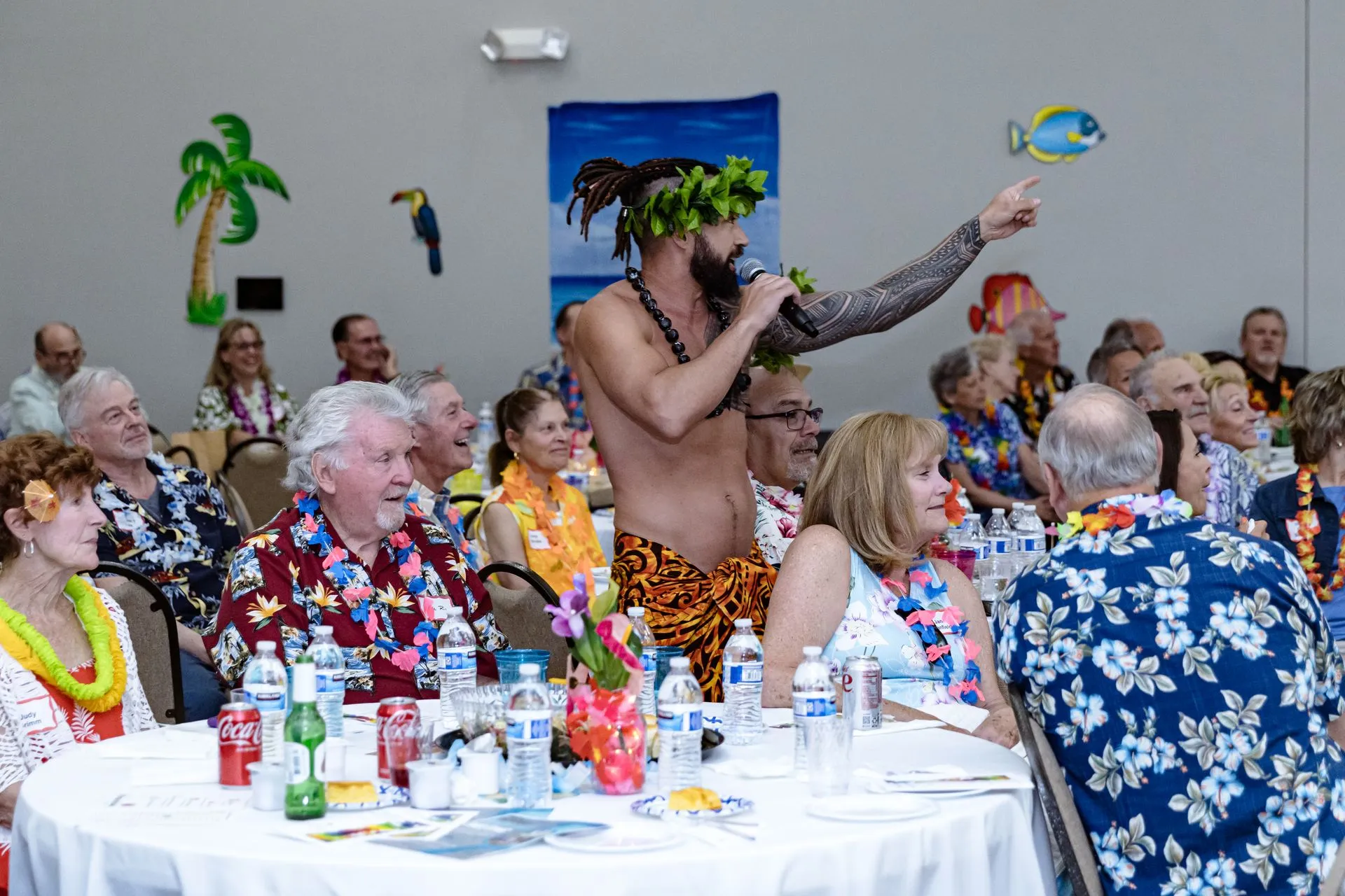 A man is singing into a microphone in front of a crowd of people sitting at tables.