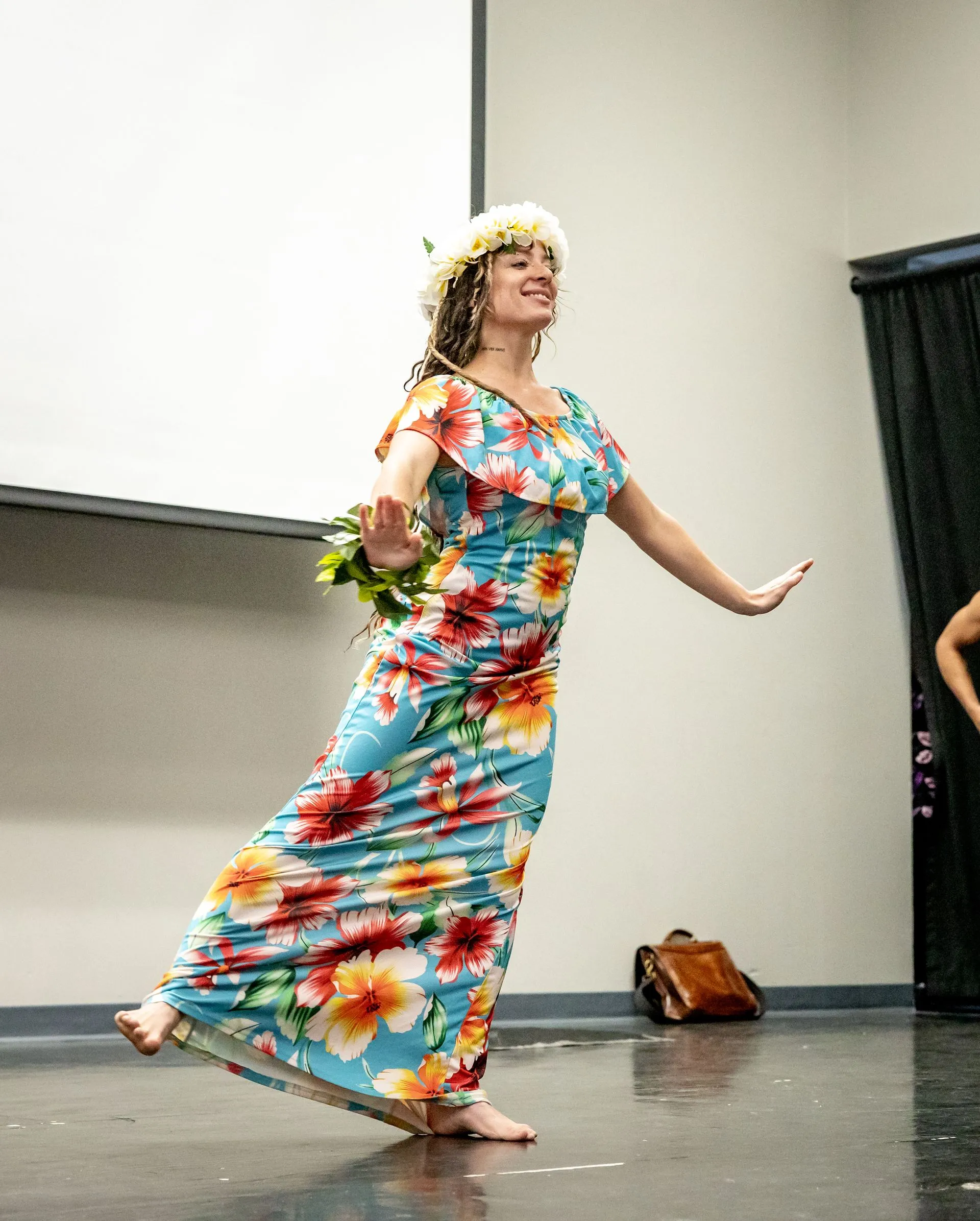 A woman in a floral dress is dancing on a stage