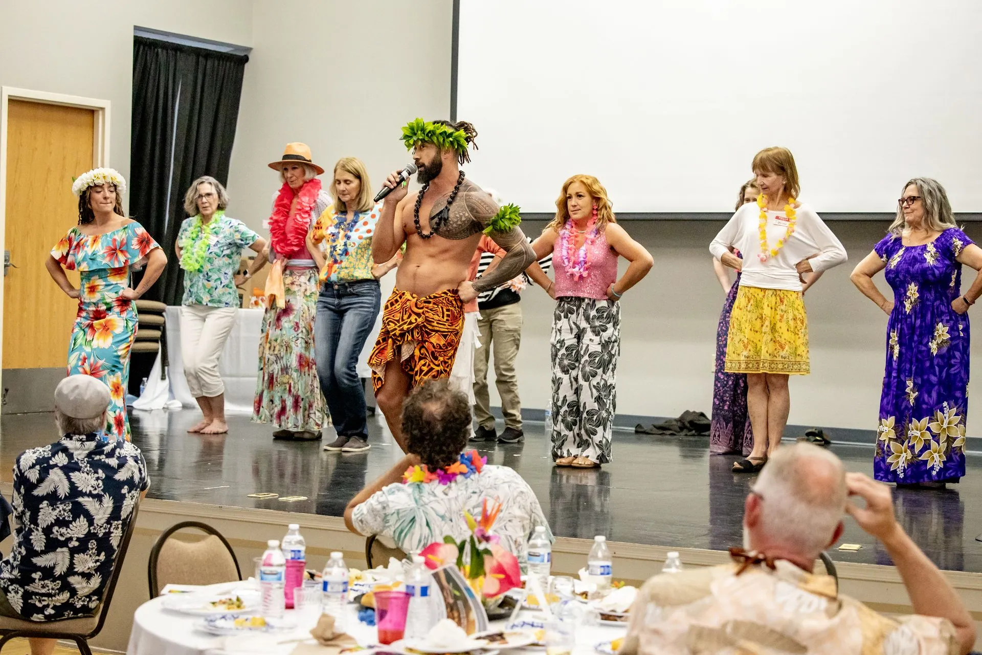 A group of people are dancing in a room while a man sings into a microphone.