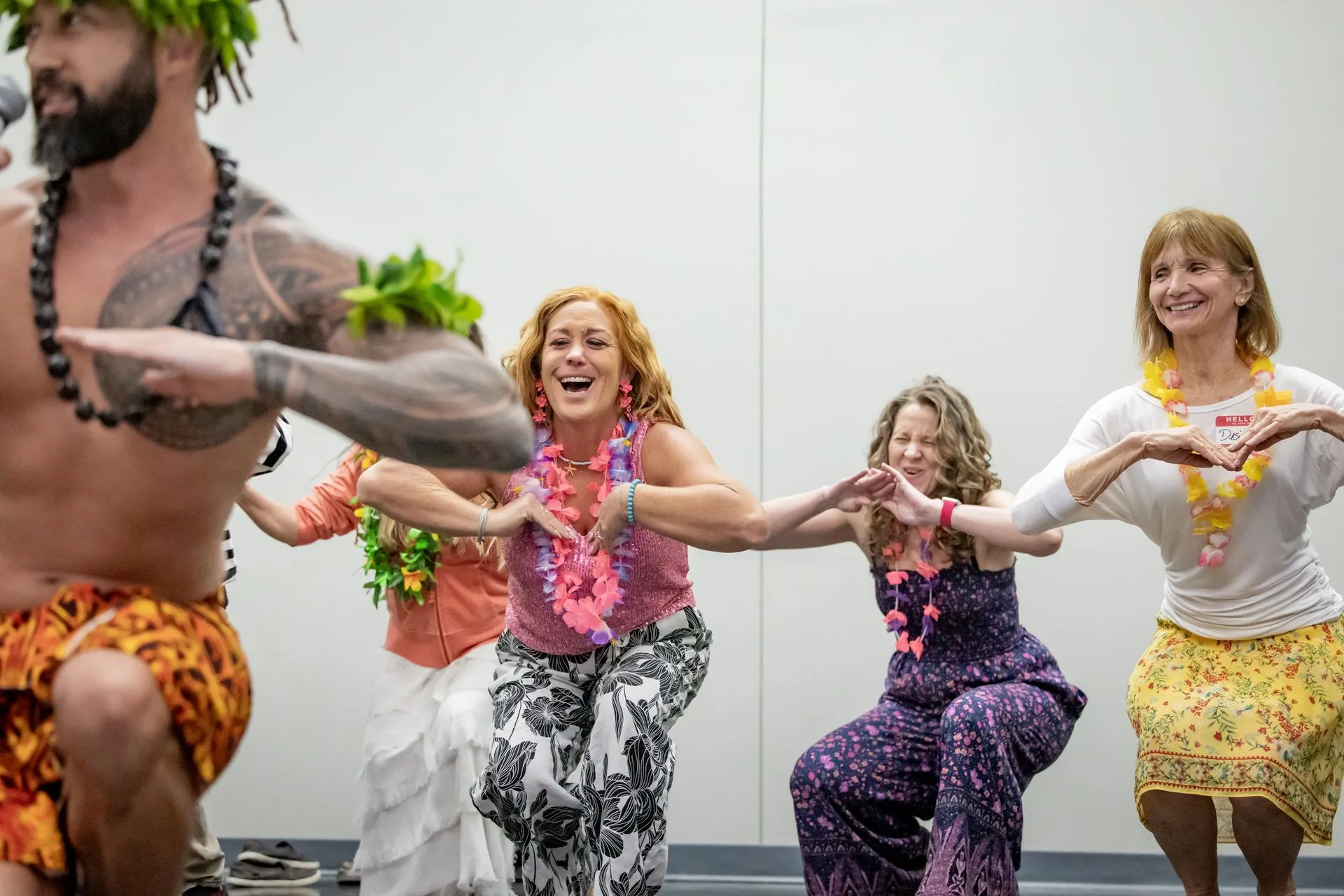 A group of people are dancing hula in a room.