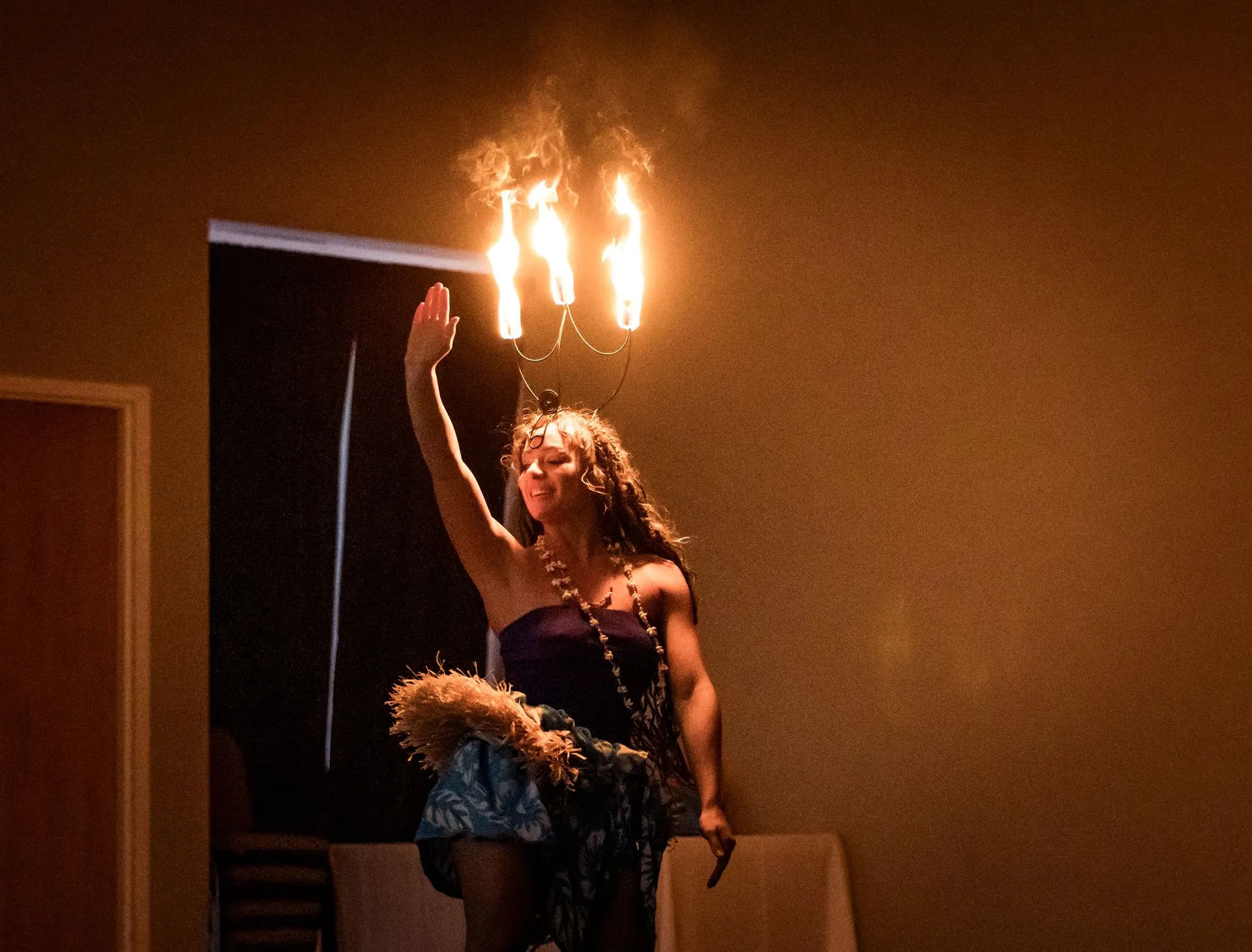 A woman in a purple dress is holding a chandelier with flames coming out of it