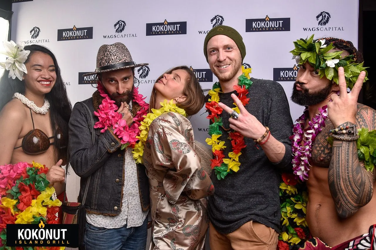A group of people posing for a picture with a sign that says kokonut