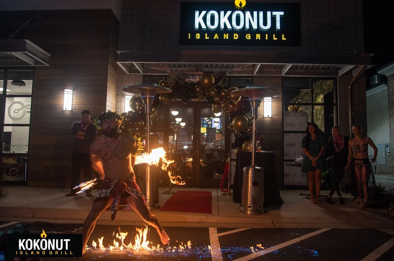 A man is playing with fire in front of a kokonut restaurant