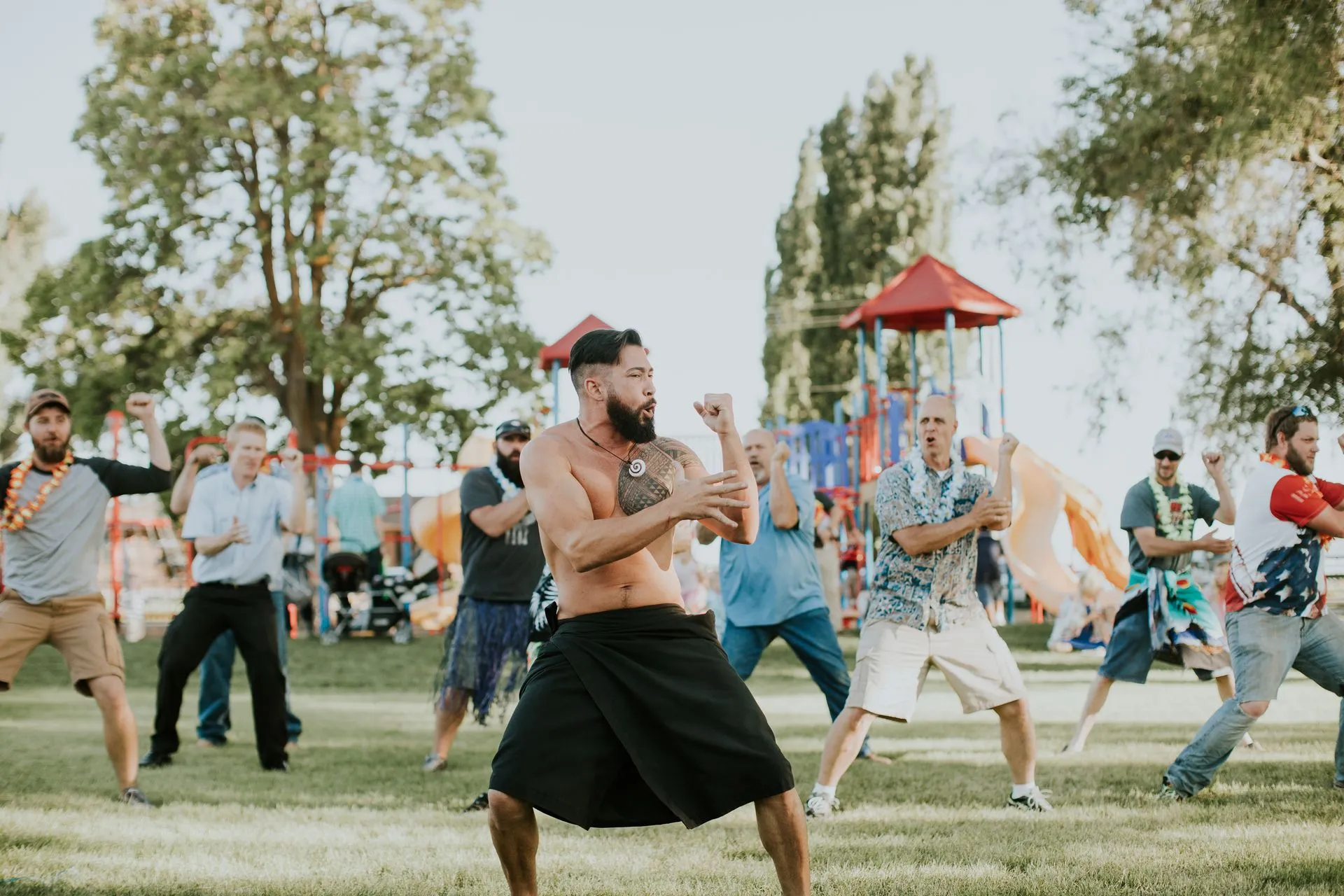 A group of men are dancing in a park.