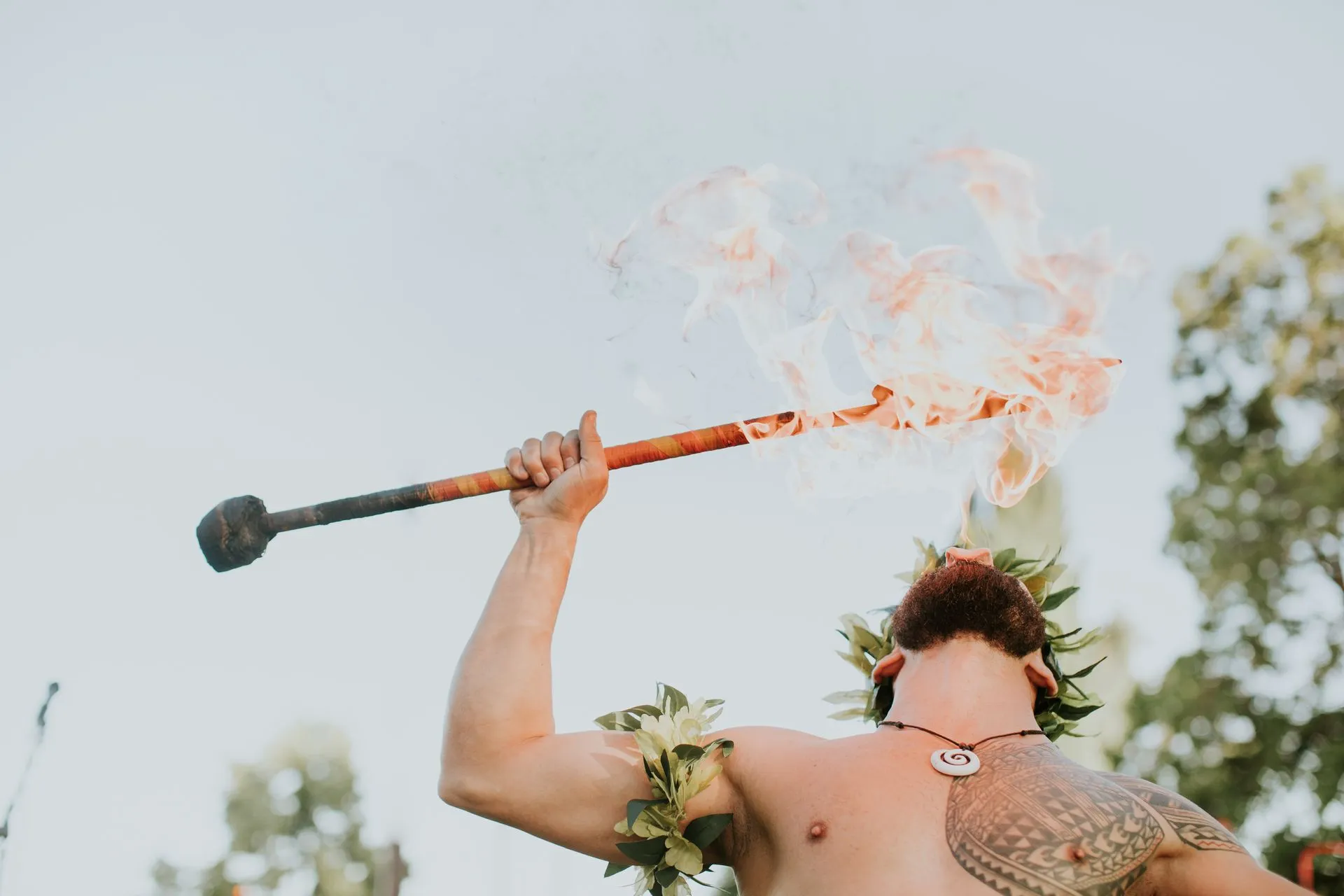 A shirtless man is holding a torch with flames coming out of it.