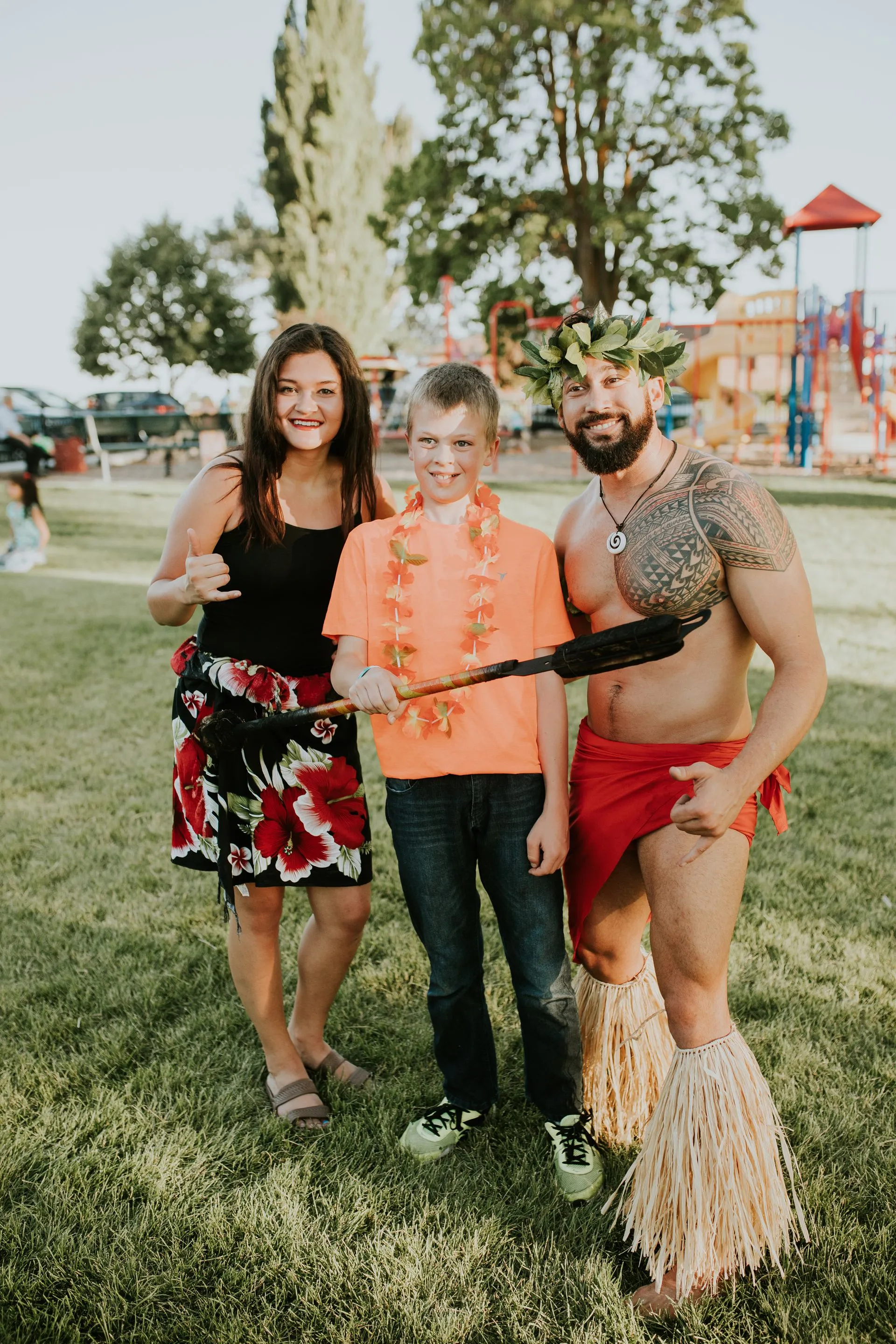 A man and a woman are standing next to a boy in a park.