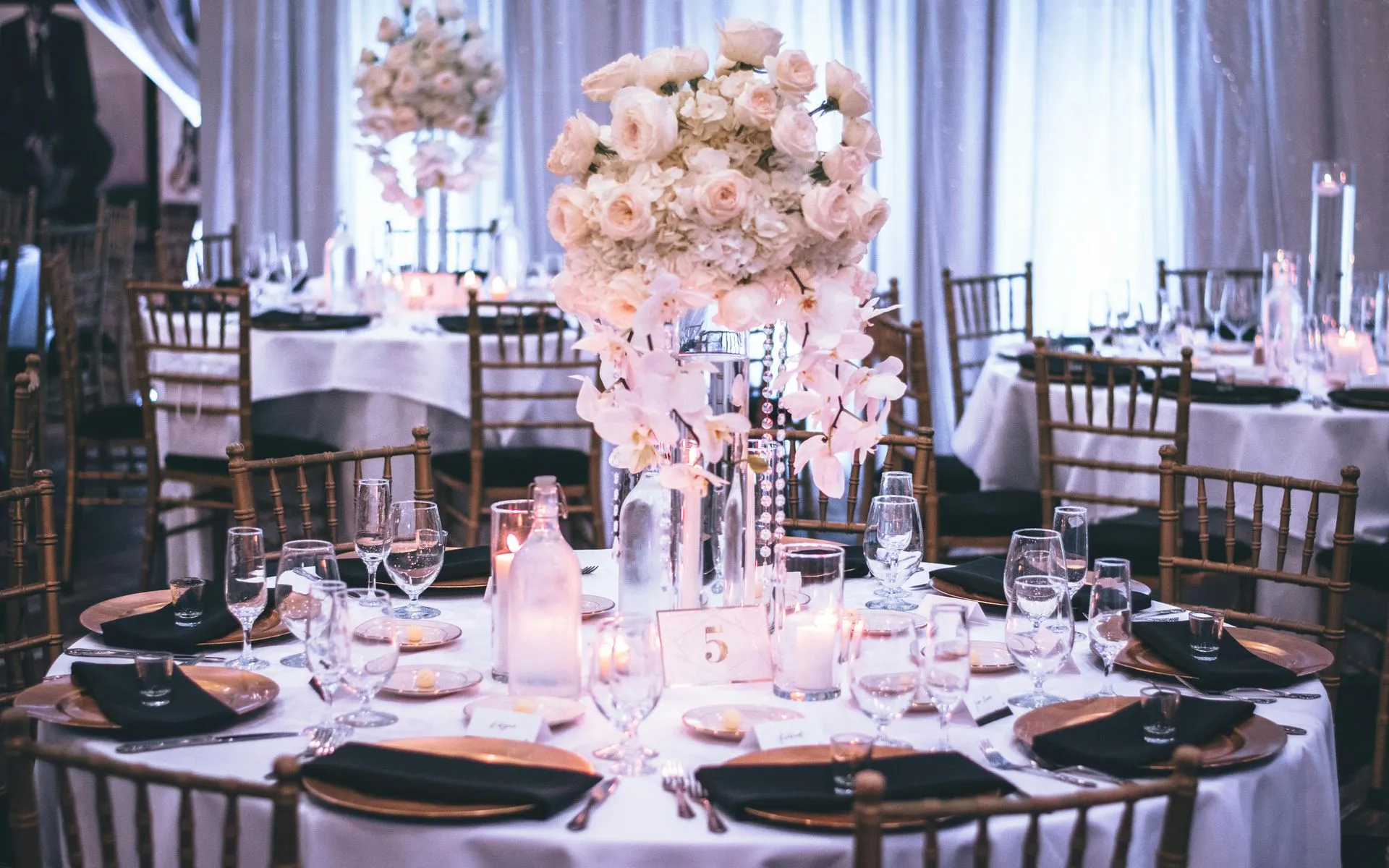 Formal banquet tables with white floral centerpieces and gold accents.