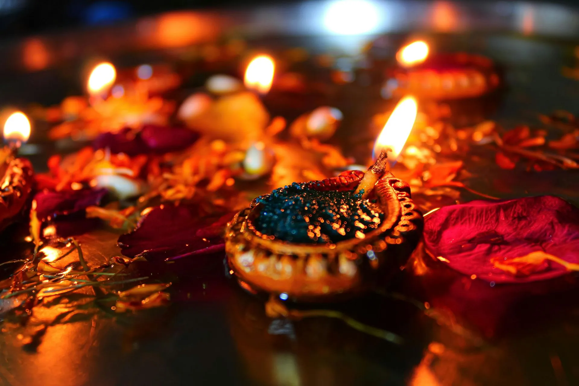 Diwali celebration with floating clay lamps in water, surrounded by flowers, radiating warm light.