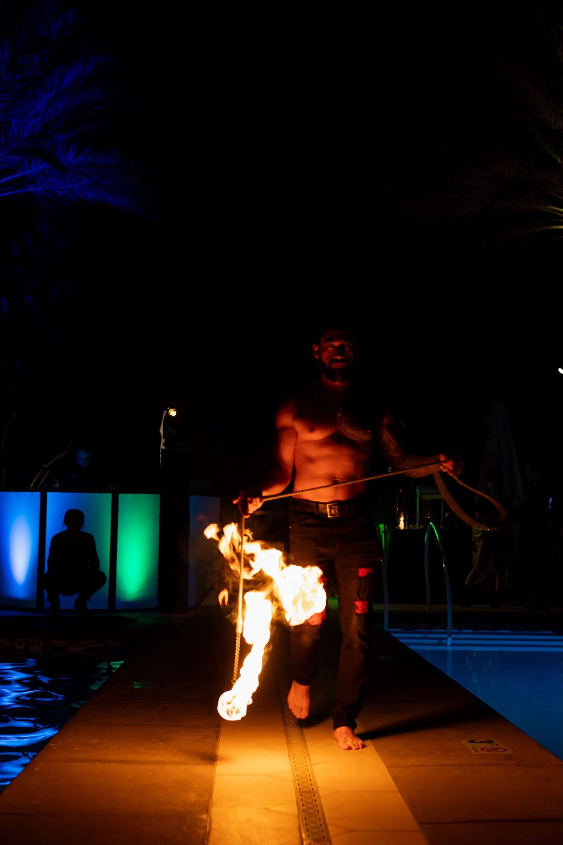 A man is walking down a sidewalk with a torch in his hand.