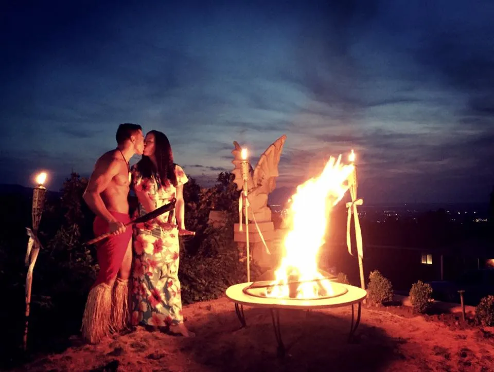A man and a woman are kissing in front of a fire.