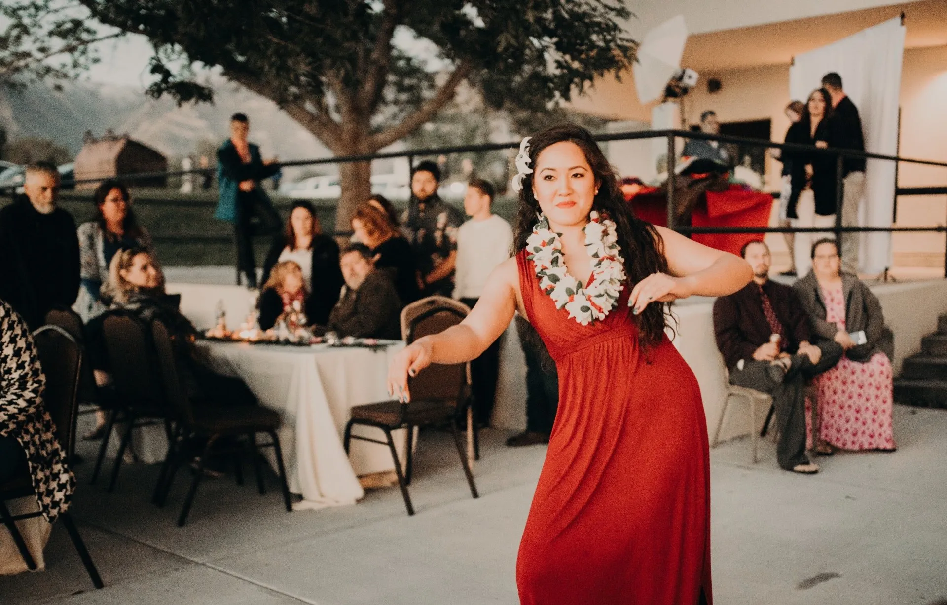 A woman in a red dress is dancing in front of a crowd at a wedding reception.
